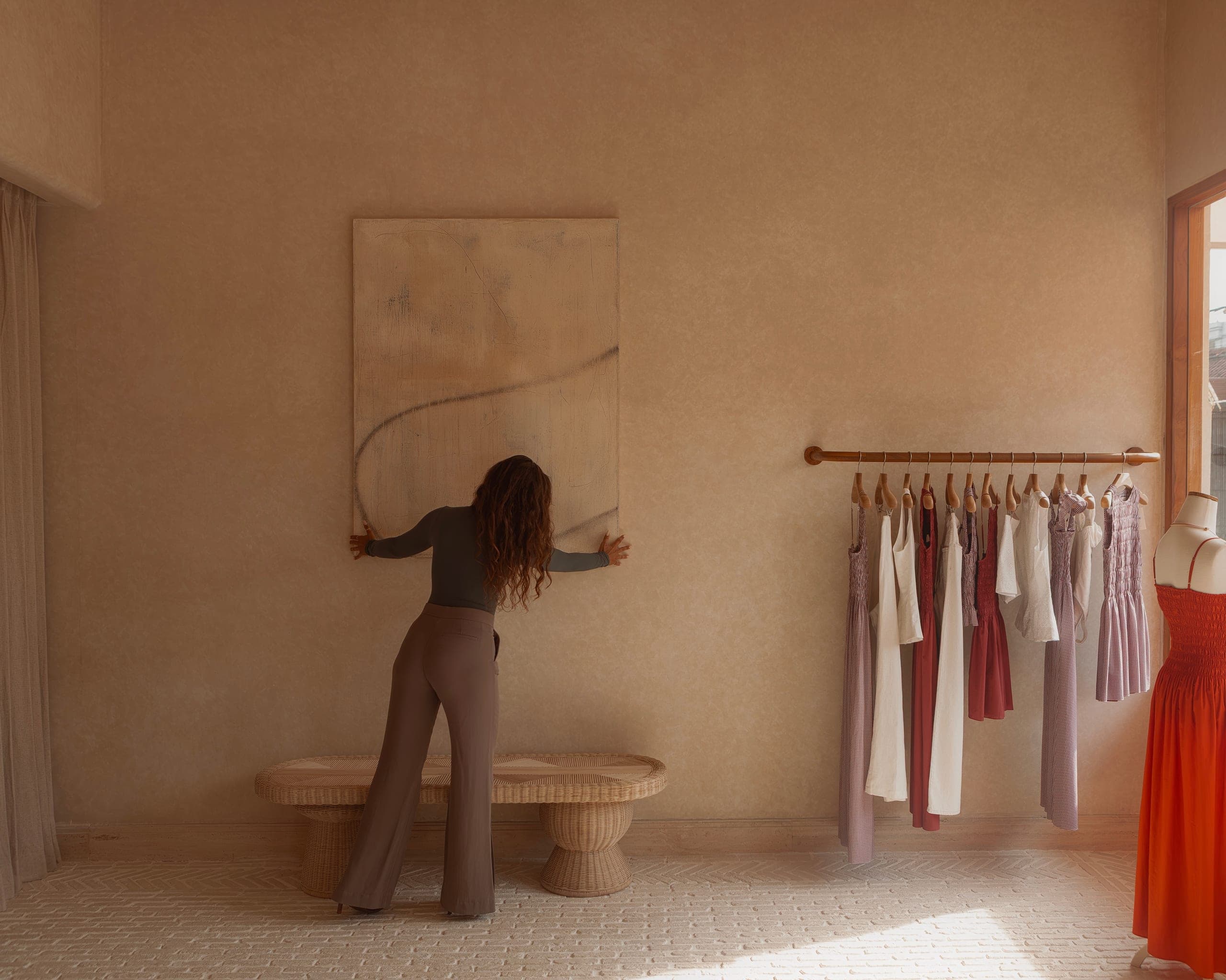 Studio showroom, a figure adjusts a canvas beside a wardrobe rack